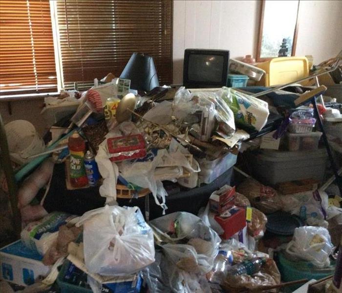 A room filled with trash and junk all the way to the window. 