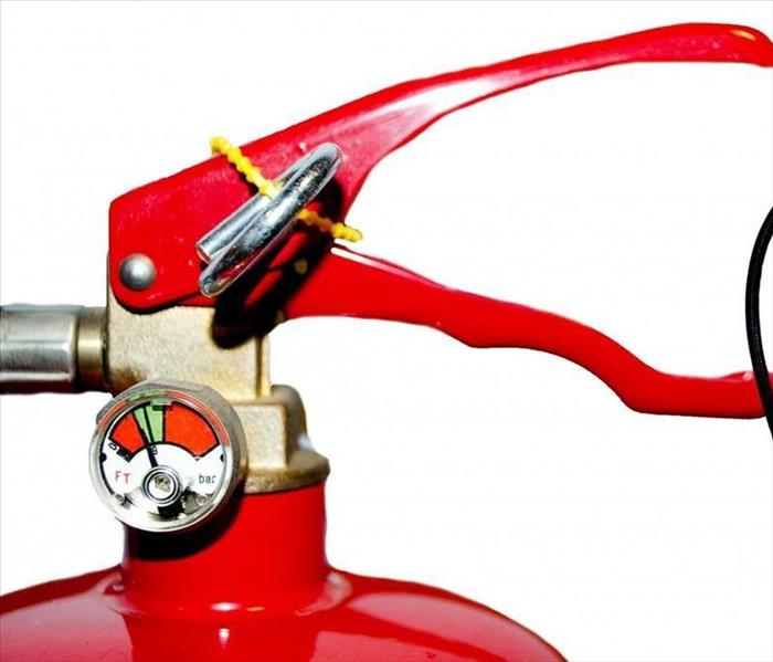 Close up of a fire extinguisher handle with a whole fire extinguisher in the background
